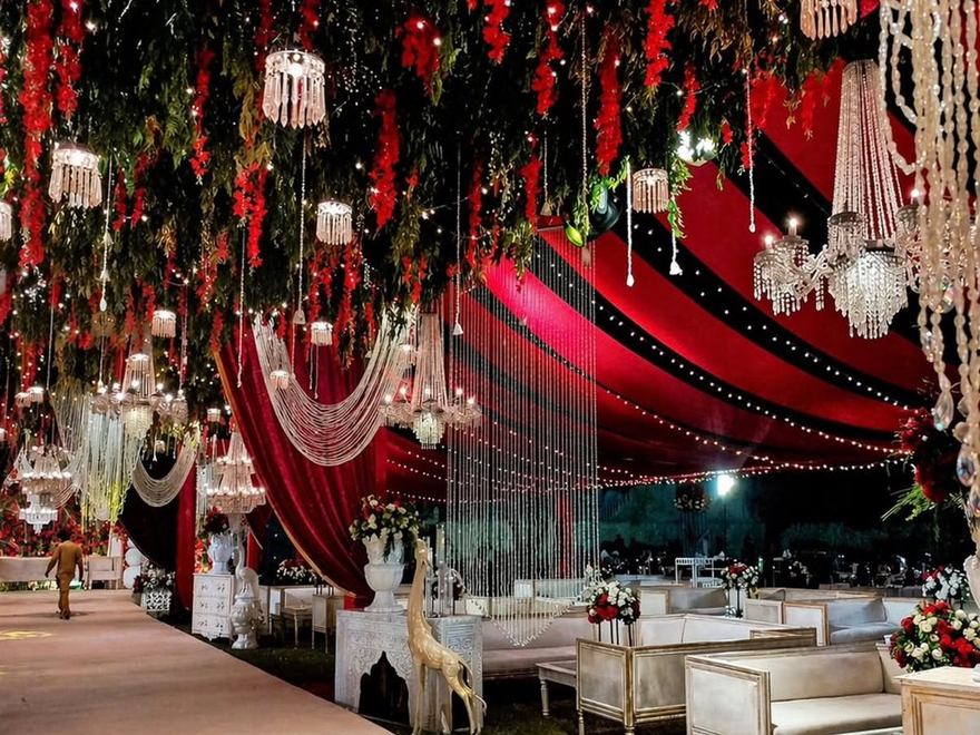 Baraat hall draped in red with crystal chandeliers by Wedding Alley
